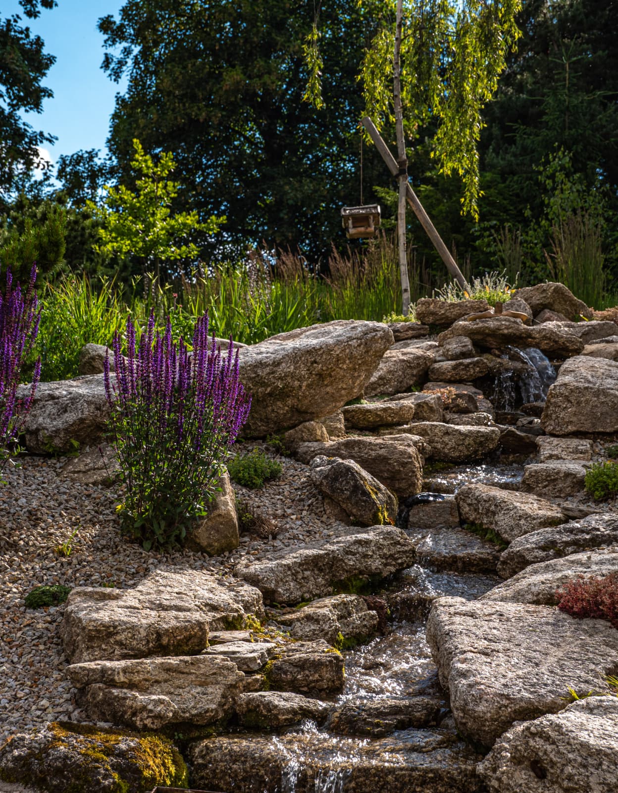 zahradní potůček s kameny a trvalkami v přírodní zahradě