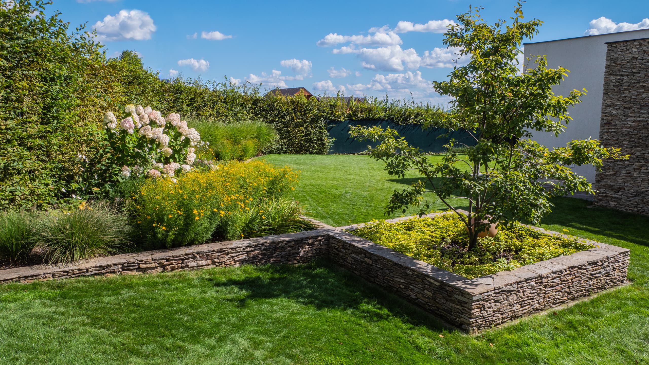 Moderní zahrada s hustým trávníkem a kamennými prvky
