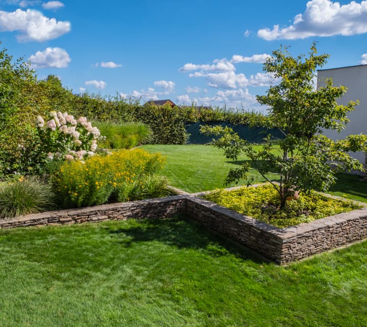 Moderní zahrada s hustým trávníkem a kamennými prvky